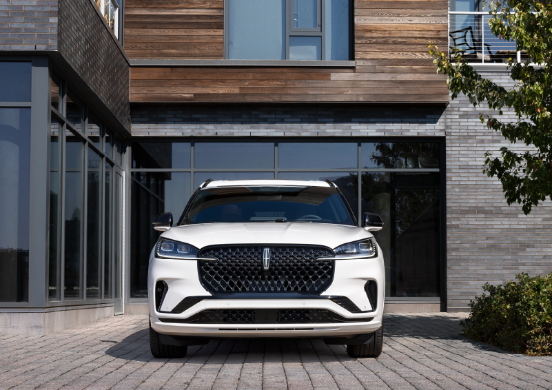 A white 2025 Lincoln Aviator® SUV is shown parked outside a modern building with gray brick and wood accents. | Kindle Lincoln in Cape May Court House NJ