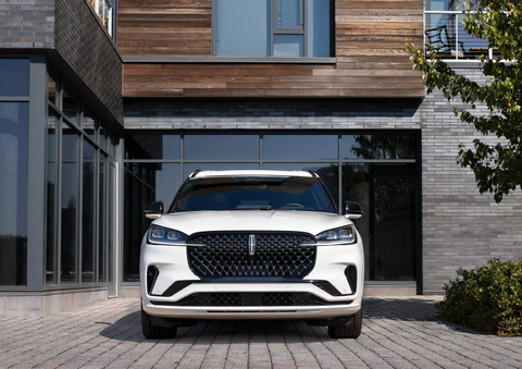A white 2025 Lincoln Aviator® SUV is shown parked outside a modern building with gray brick and wood accents. | Kindle Lincoln in Cape May Court House NJ