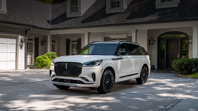 A white 2026 Lincoln Aviator® SUV is parked in the driveway of a luxury home. | Kindle Lincoln in Cape May Court House NJ