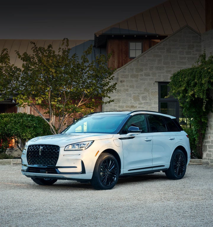 A 2025 Lincoln Corsair® SUV is parked in front of a stately home.